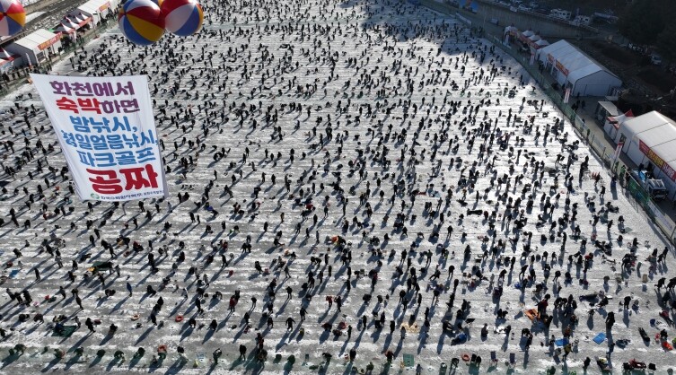 관광객은 얼음속 산천어를 낚고 화천은...